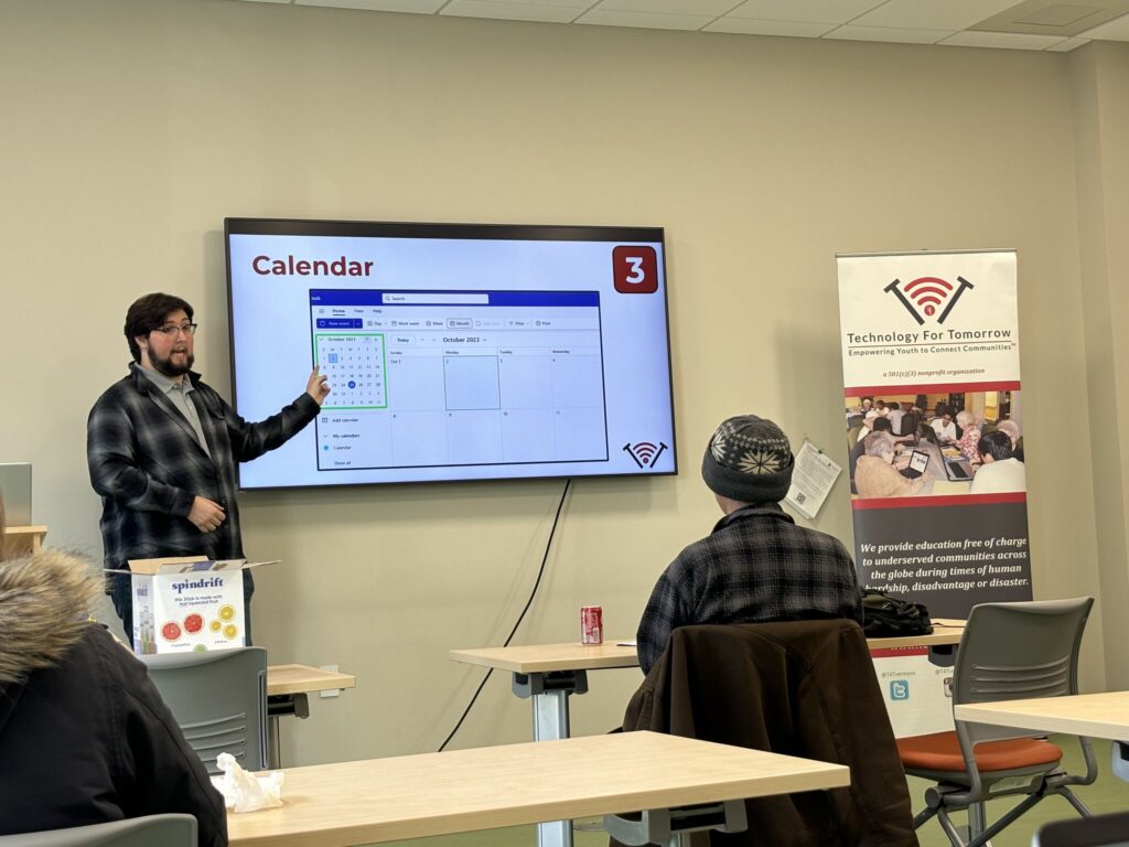 T4T Trainer points at a board labeled Calendar to a classroom of older students.